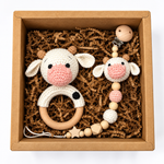 Handmade crochet cow baby rattle and matching cow pacifier holder in kraft gift box