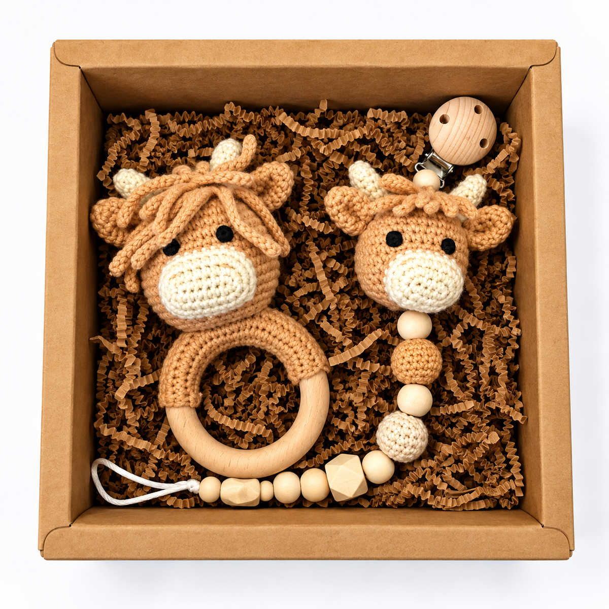 Handmade crochet Highland cow baby rattle and matching pacifier holder in a kraft gift box